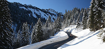 Auto fährt durch verschneite Berglandschaft.