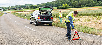 Mann stellt nach einer Panne ein Warndreieck auf