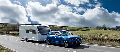 Pkw fährt mit Wohnanhänger auf Straße