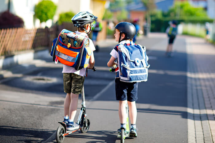 Jungs mit Roller auf dem Weg zur Schule